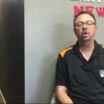 Joe McConnell sitting in front of a grey wall, wearing a black shirt at Elk City Motor Sports Park