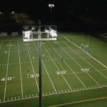 put alt text here. alt text is what shows when the images doesn't load. also what vision impared people hear. Aerial view of two women’s soccer teams playing under stadium lights on a turf field at night in St. Mary Parish